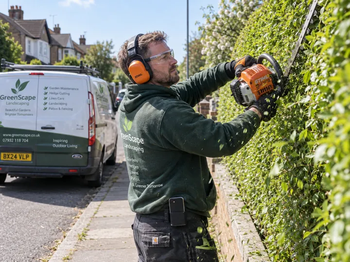Gardener trimming while AI handles incoming booking call