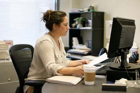 A property manager reviewing leases and maintenance tickets on property management software at a desk