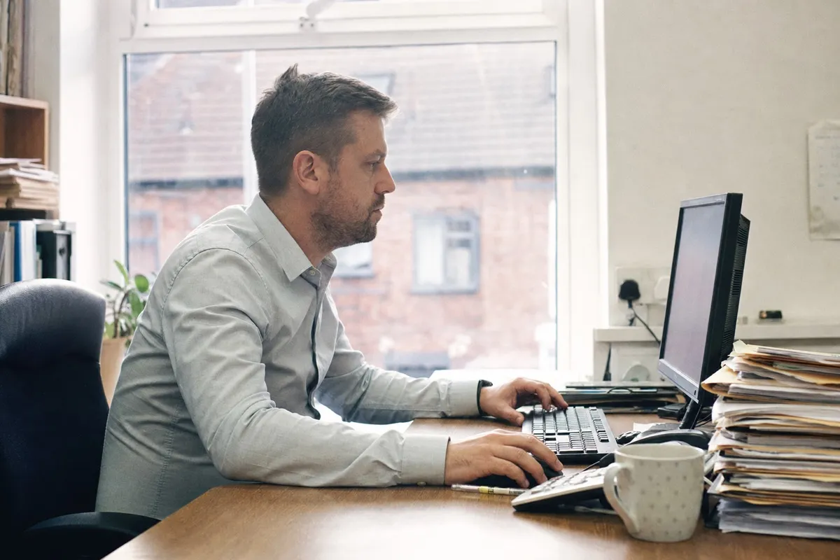 A lettings manager reviewing tenancies and maintenance jobs on property management software at a desk