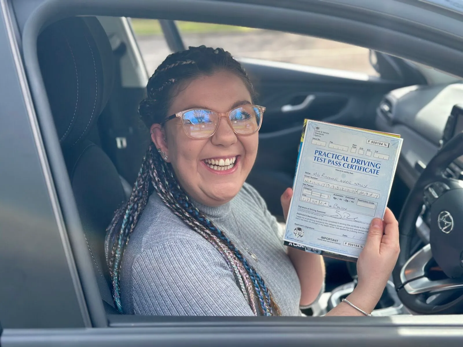 A Get Driving Today pupil smiling in the car with her driving test pass certificate