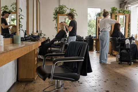An empty styling chair in a busy New Zealand salon while stylists work the other stations