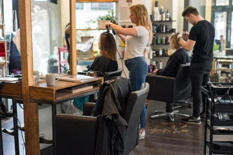 An empty styling chair in a busy salon while stylists work the other stations