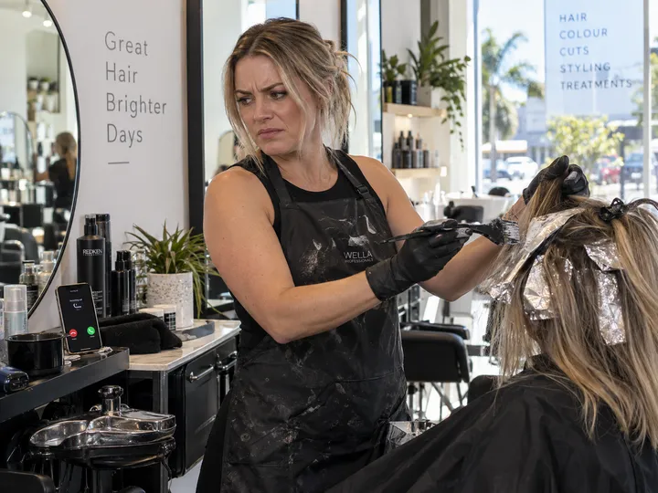 Hairstylist unable to answer phone while applying colour to a client