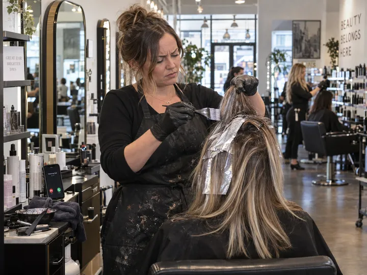 Hair stylist unable to answer phone while applying color to a client