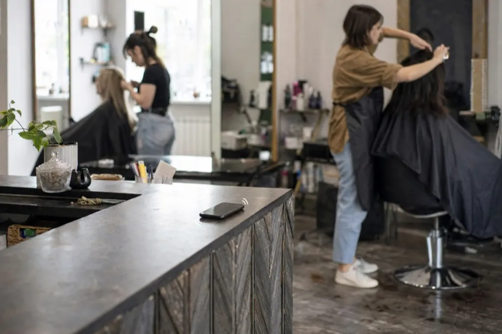 A salon phone ringing on an empty front desk while stylists work in the background