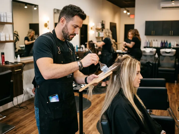 Hairstylist applying colour while AI handles incoming booking call