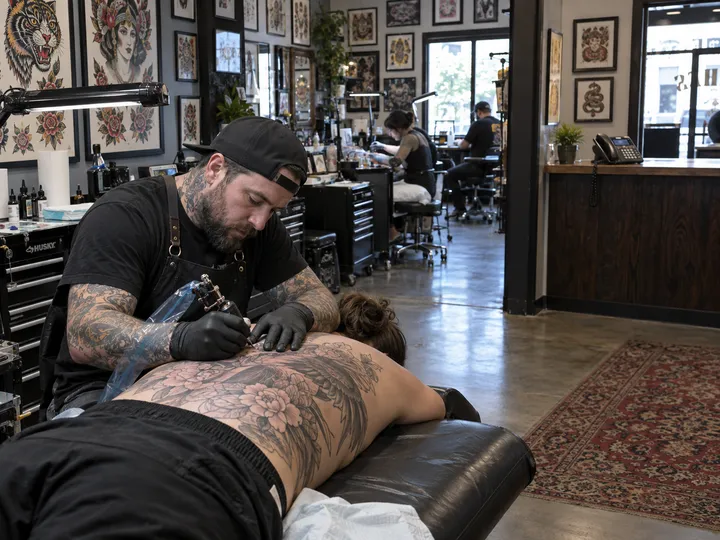 Tattoo artist mid-session while AI handles shop phone calls