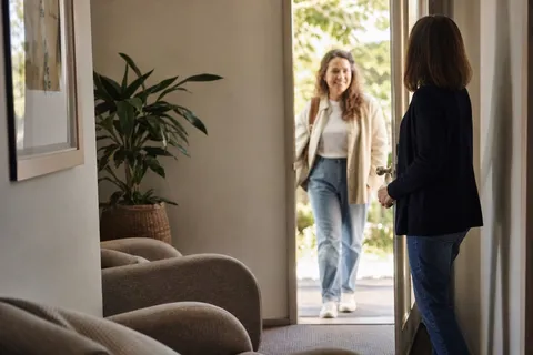 A therapist welcoming a client into a warm consulting room.