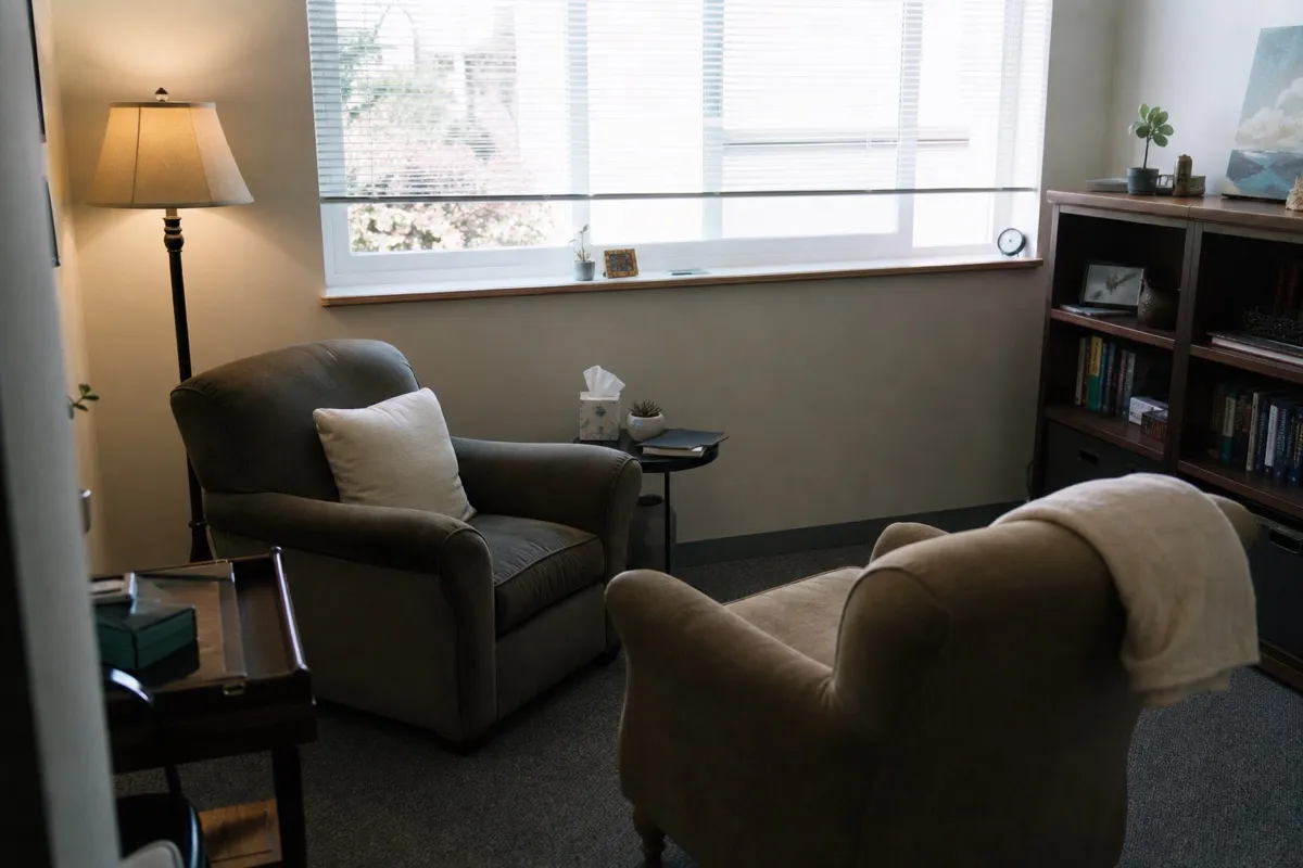 A calm private therapy room with two armchairs and soft daylight.