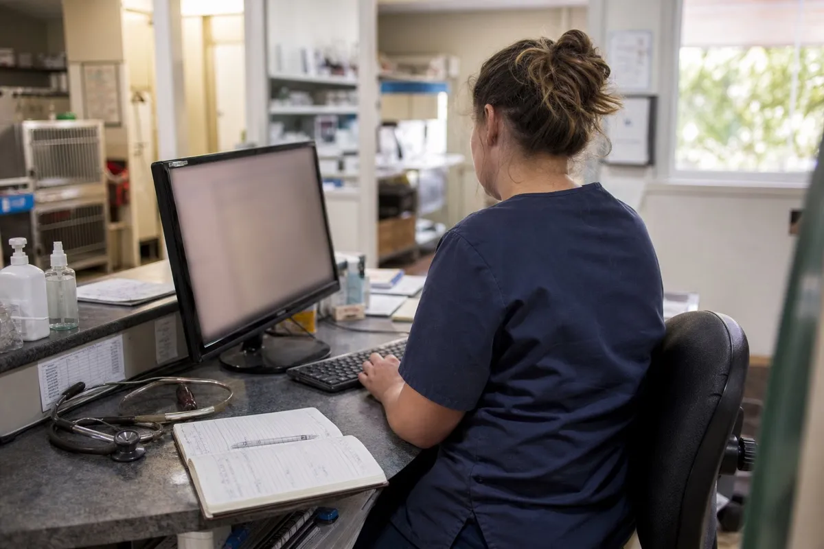 A veterinary nurse checking the day's appointments on the front-desk computer.
